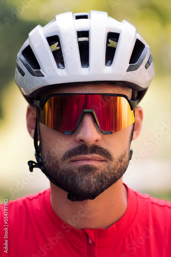 portrait of a young cyclist wearing a helmet and cycling goggles looking at camera with a defiant attitude © Raul Mellado