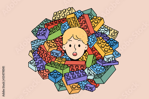 Cute boy child head in pile of blocks constructor. Stunned small kid playing with construction set. Children hobby concept. Vector illustration.