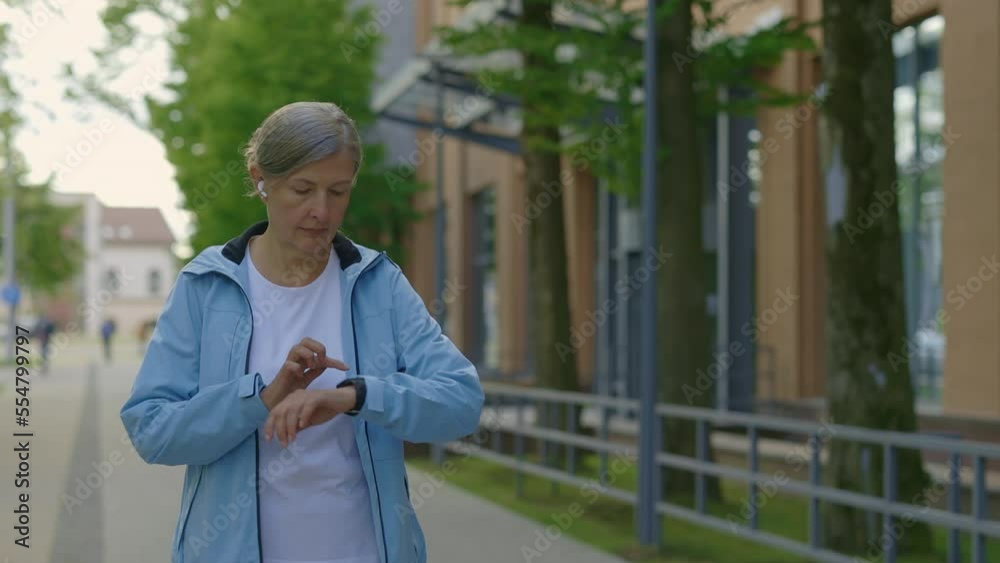 Senior female athlete starts to run and using smart watch before running. Workout equipment app technology monitor active gadget jogger. Sport and healthy lifestyle concept Senior female athlete starts to run and using smart watch before running. Workout equipment app technology monitor active gadget jogger. Sport and healthy lifestyle concept
