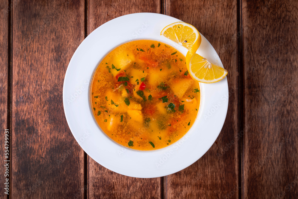 soup with fish and lemon on a wooden background soup with fish and lemon on a wooden background