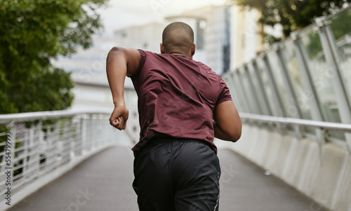 Back, black man and running outdoor, workout and training for marathon, wellness and health. African American male, athlete and runner practice on street, fitness and exercise for energy and cardio.