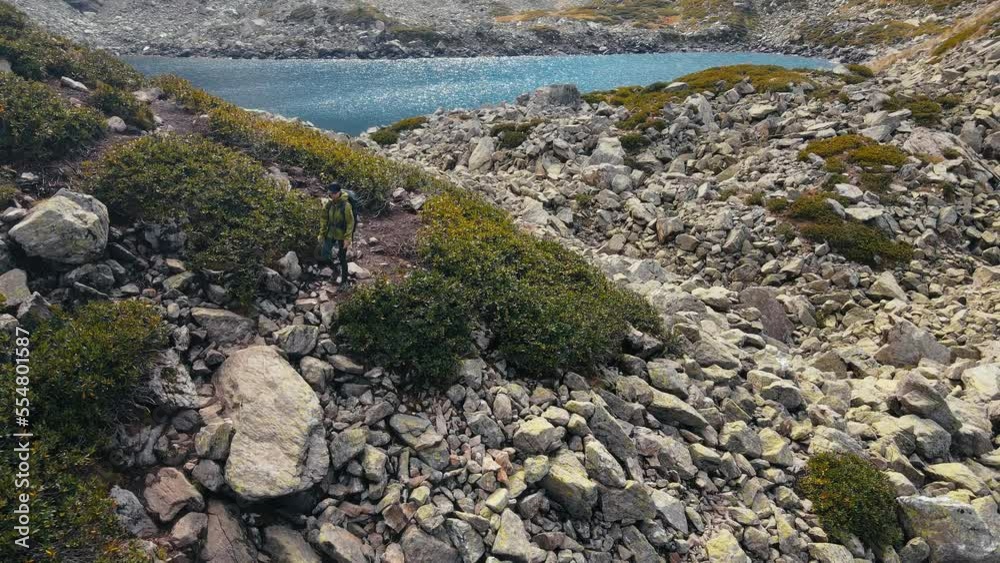Solo hiker woman trekking at mountain lake in highland. aerial view Solo hiker woman trekking at mountain lake in highland. aerial view