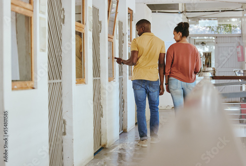 Animal shelter, adoption and charity with a black couple together in a rescue center for community aid. Help volunteer and ngo with a man and woman walking through a kennel for pet adoption photo