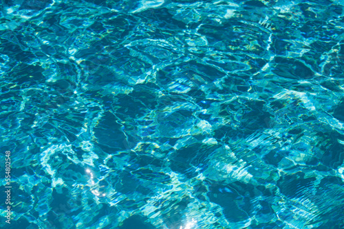 Water background, ripple waves. Blue swiming pool pattern. Sea surface. Water in swimming pool with sun reflection. Banner with copy space. © Volodymyr