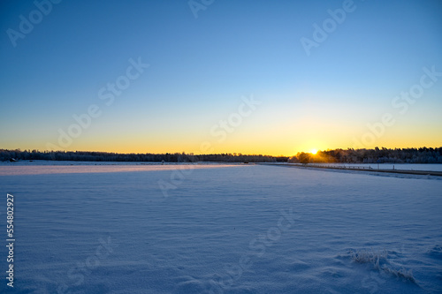 Sunrise a cold morning over field covered in snow
