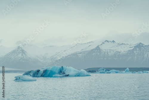 Blue icebergs floating near coast landscape photo. Beautiful nature scenery photography with mountain on background. Idyllic scene. High quality picture for wallpaper, travel blog, magazine, article