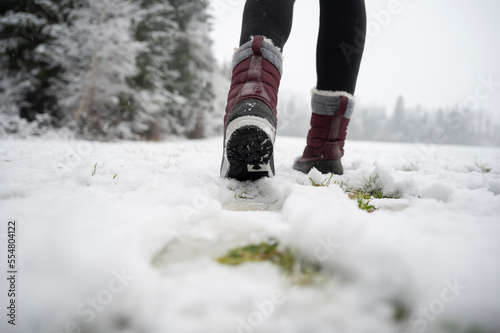 Obraz na plátne Low angle view of female legs with snow boots walking in winter nature