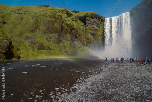 Famous Skogafoss waterfall on cliff landscape photo. Beautiful nature scenery photography with rocks on background. Idyllic scene. High quality picture for wallpaper, travel blog, magazine, article