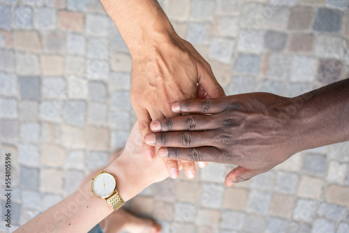 Multiracial friends stacking hands over footpath photo