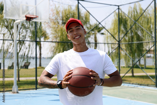 Smiling man holding basketball at sports court
