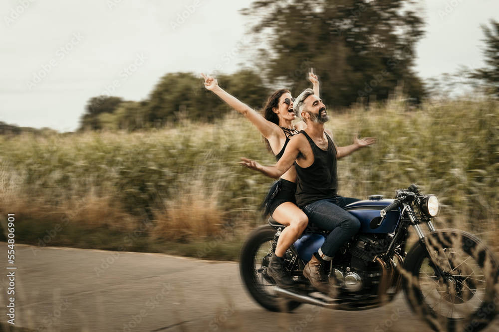 Mature man and woman riding motorcycle on road Mature man and woman riding motorcycle on road