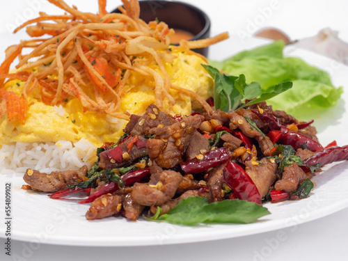 Stir Fried Basil with pork and topped scrambled eggs, crab sticks isolated on white background.