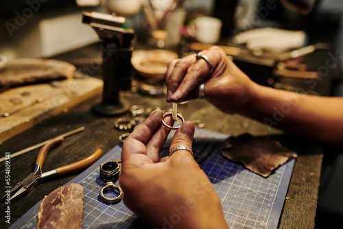 Hands of craftswoman repairing ring at workbench photo