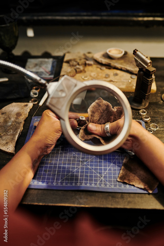 Hands of jeweller polishing golden ring with sand paper on workbench
