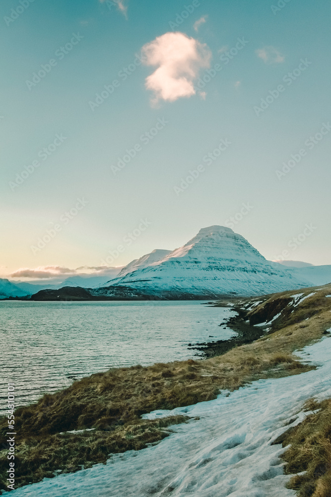 Snowy mountain near sea bay landscape photo. Beautiful nature scenery photography with cloudy sky on background. Idyllic scene. High quality picture for wallpaper, travel blog, magazine, article
