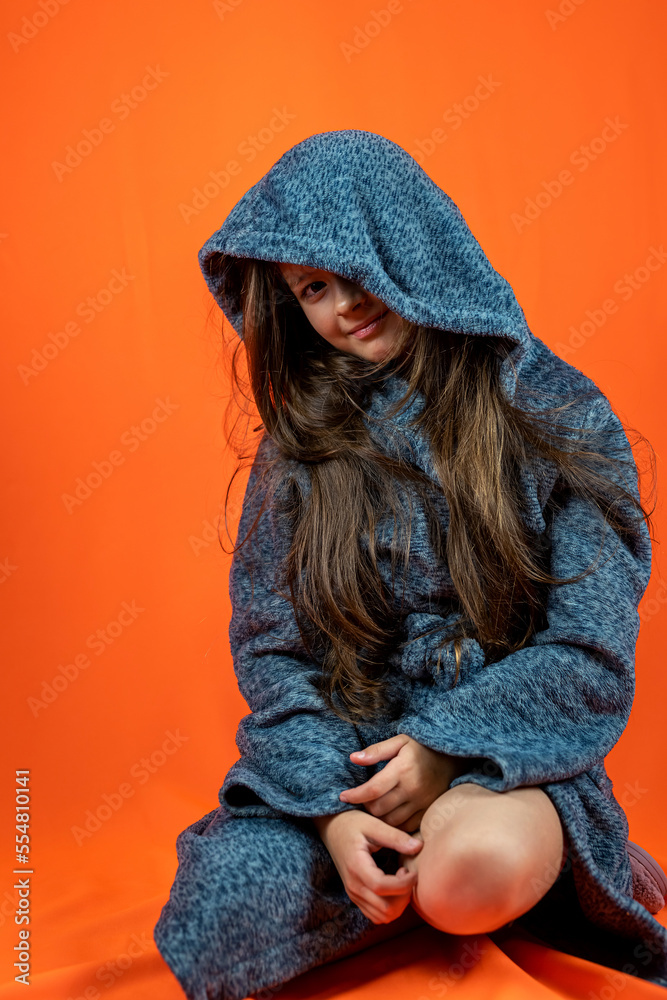 pretty girl in a gray robe with dark hair is happy on a peach background. pretty girl in a gray robe with dark hair is happy on a peach background.