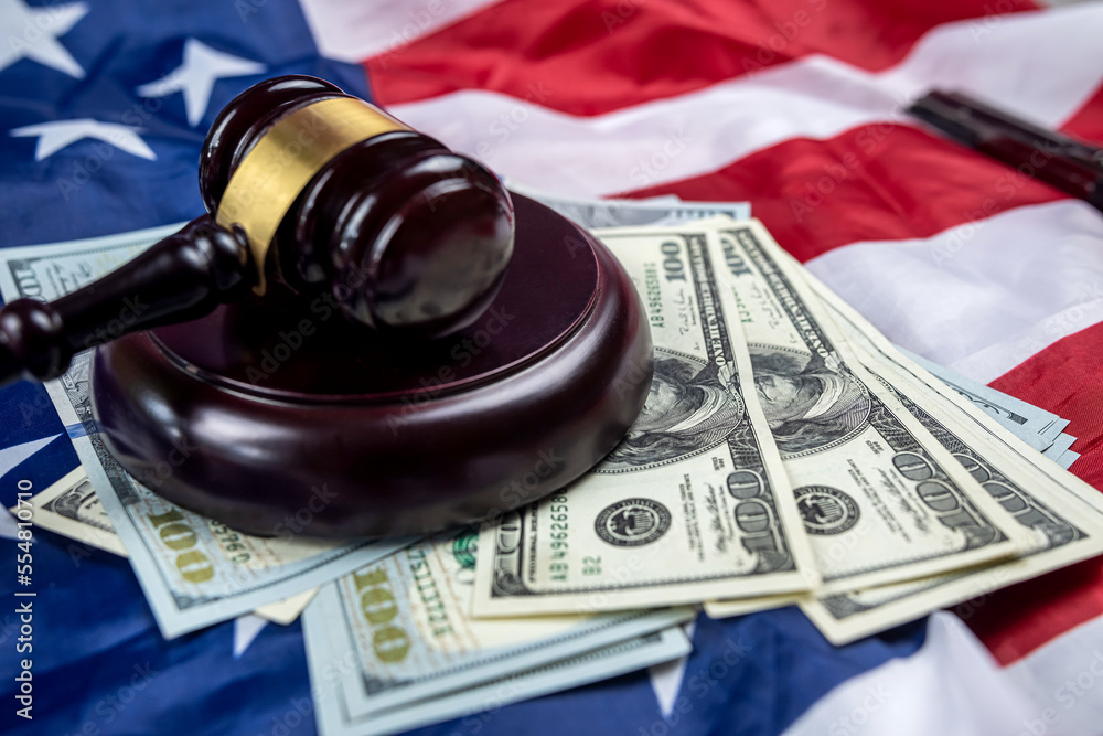 hundred dollar bills and a judge's gavel are placed on an American flag.