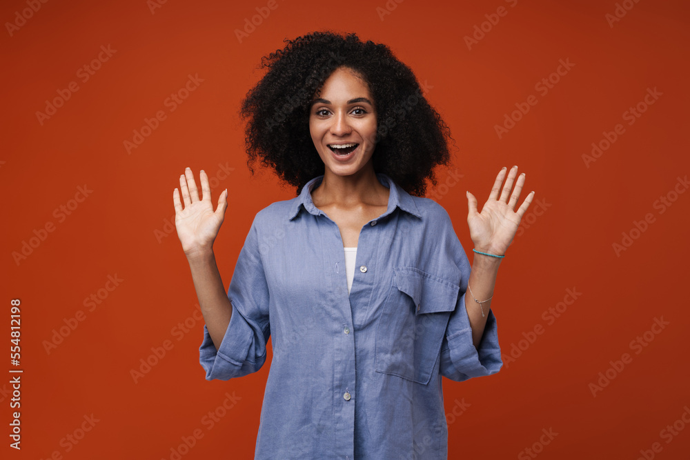 Young middle-eastern woman with curly hair smiling and raising her arms Young middle-eastern woman with curly hair smiling and raising her arms
