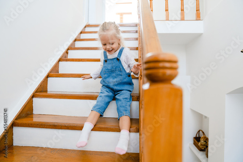 Φωτογραφία Little girl laughing and having fun while playing on stairs at home