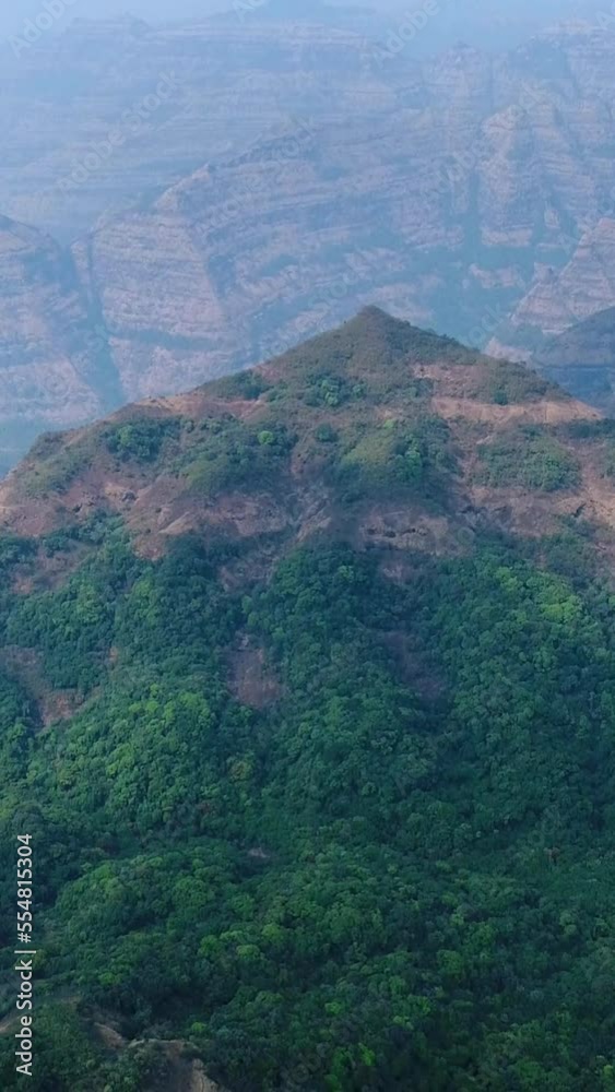 Vertical aerial video of green valley between rocky hills with steep cliff sides Vertical aerial video of green valley between rocky hills with steep cliff sides
