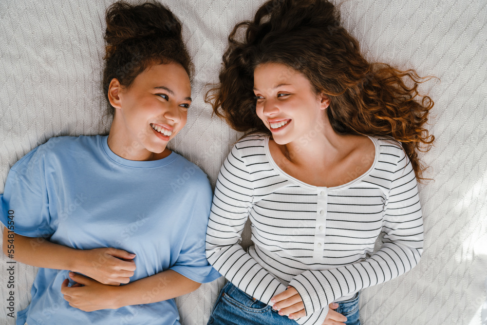Two girls laughing while lying in bed together Two girls laughing while lying in bed together
