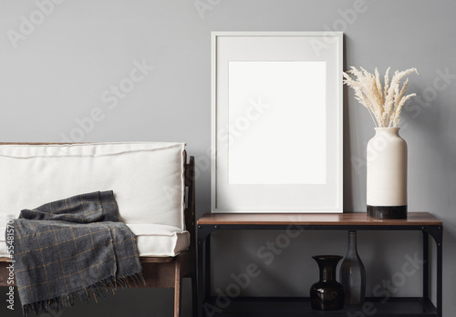 Blank picture frame mockup on gray wall. Modern living room design. View of scandinavian rustic style interior with chair. Home staging and minimalism concept