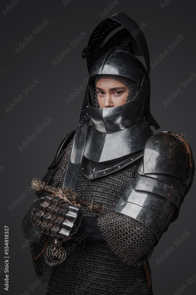 Isolated on grey background female knight from past with chainmail and sword.