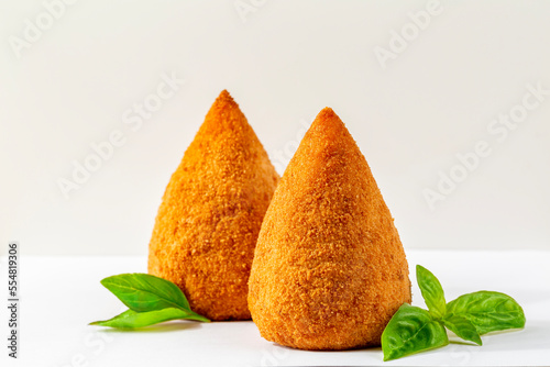  Italian rice balls that are stuffed, coated with breadcrumbs and deep fried.  Filled with ragù, mince meat, cheese and green peas. Conical-shaped arancini. Sicilian food. photo