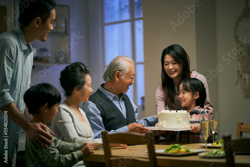 senior asian couple celebrating wedding annversary with three generational family