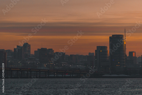 Beautiful winter view of the city of Dnipro during sunset or sunrise. Winter landscape. Ukrainian city. The lights of a sun. Calm nature copies the space background. © Denis Chubchenko