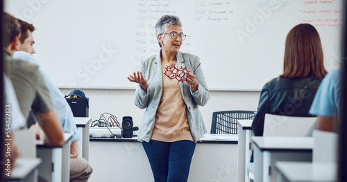 Education, university professor and students in classroom for lecture on innovation in science, physics or math. Focus, attention and woman college teacher in presentation with diversity in learning. photo