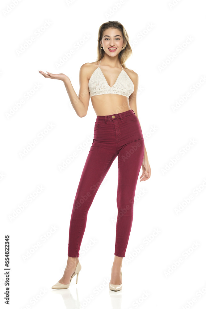 Smiling Woman In Burgundy Jeans And Top Presenting Something On her Empty Palm On A White Background Smiling Woman In Burgundy Jeans And Top Presenting Something On her Empty Palm On A White Background
