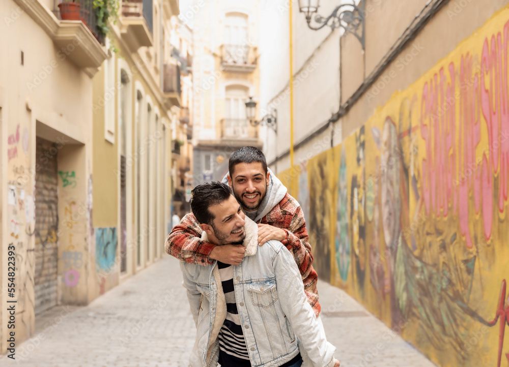 Smiling gay man piggybacking male partner while on the street