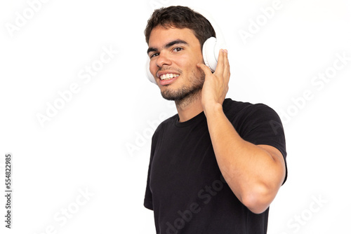 Happy young man listening to music. Pleased Caucasian male model with short dark hair in black T-shirt looking at camera, smiling, enjoying song in headphones. Modern technology, music concept