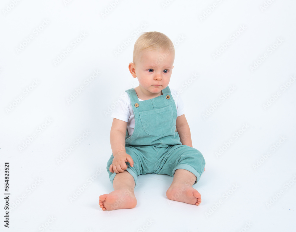 Close-up portrait of beautiful baby boy wearing light blue jumpsuit over white studio background smiling and looking to the camera. Close-up portrait of beautiful baby boy wearing light blue jumpsuit over white studio background smiling and looking to the camera.