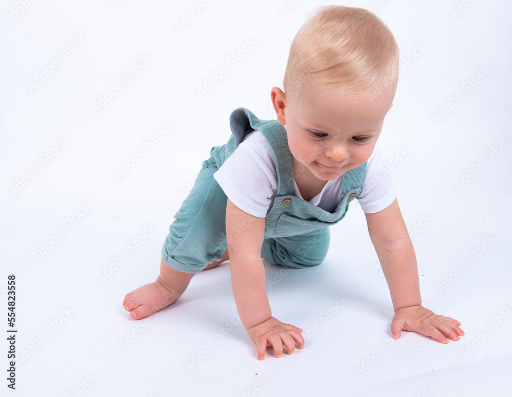 Close-up portrait of beautiful baby boy wearing light blue jumpsuit over white studio background crawling to his parents, wants to play. Close-up portrait of beautiful baby boy wearing light blue jumpsuit over white studio background crawling to his parents, wants to play.