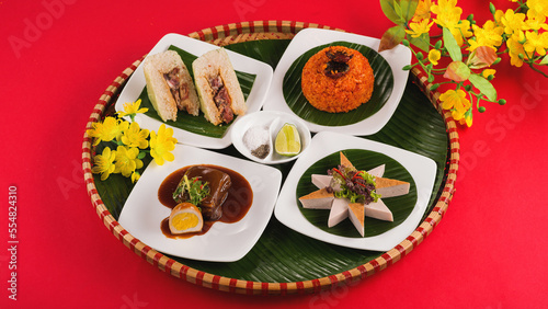 Family dinning table of Tet holiday or Lunar New Year with traditional foods: pork belly and eggs braised in coconut water, pickles, rice, Banh Tet (rice cake), fried vegetables, bitter melon soup.  photo