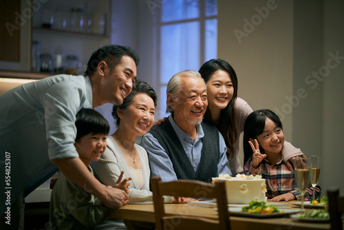 senior asian couple celebrating wedding annversary with three generational family
