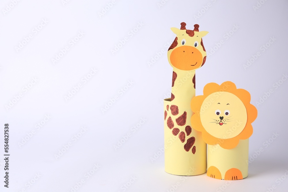 Toy giraffe and lion made from toilet paper hubs on white background, space for text. Children's handmade ideas
