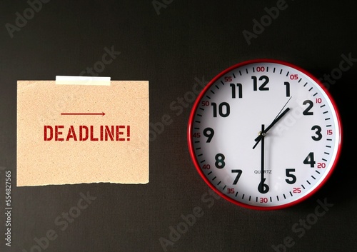 Red clock on dark copy space wall background with stick note written DEADLINE ,concept of time running out , time management to not miss a due date or a deadline