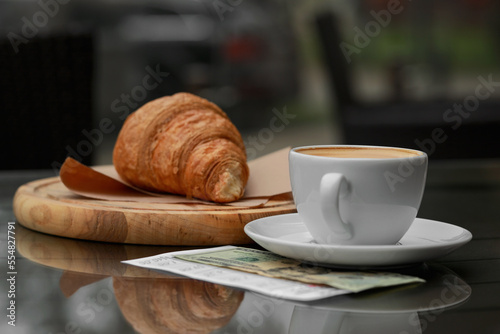 Croissant  coffee  tips and receipt on table