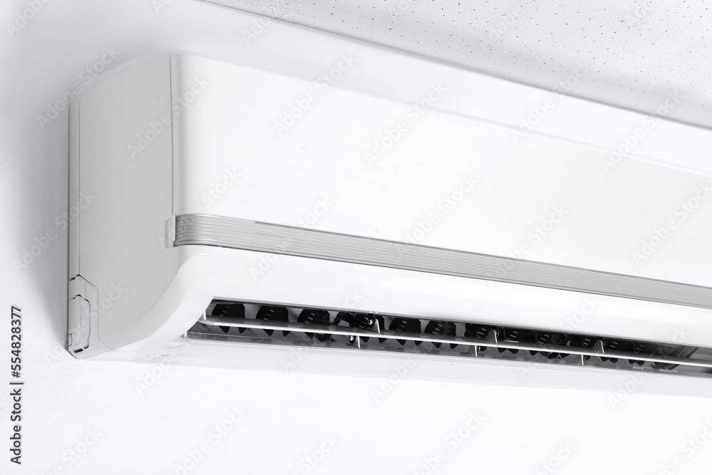 Modern air conditioner on white wall indoors, closeup Modern air conditioner on white wall indoors, closeup