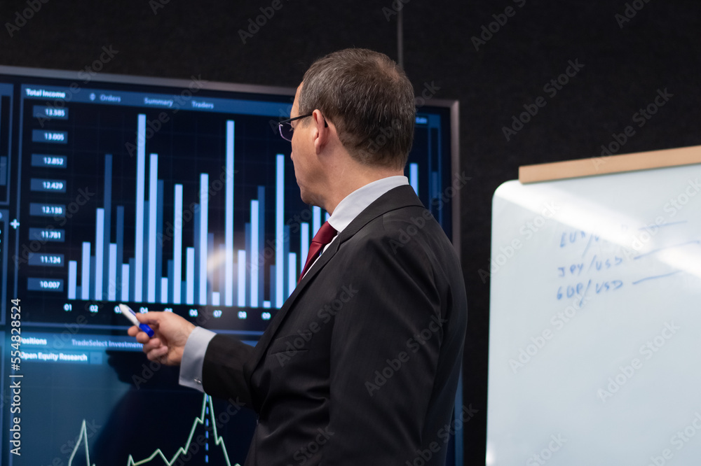 Back view of financier analyzing market reports. Serious man looking at displays, focused on checking global currency index comparing growth. Financial analytics, investment activity concept Back view of financier analyzing market reports. Serious man looking at displays, focused on checking global currency index comparing growth. Financial analytics, investment activity concept