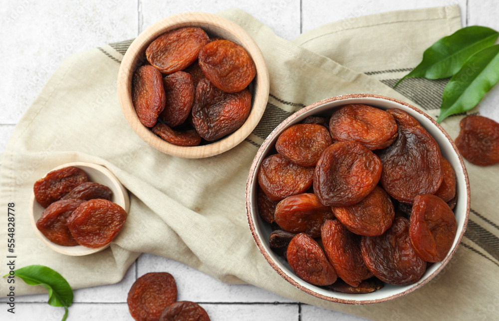 Tasty apricots with leaves on white tiled table, flat lay. Dried fruits Tasty apricots with leaves on white tiled table, flat lay. Dried fruits