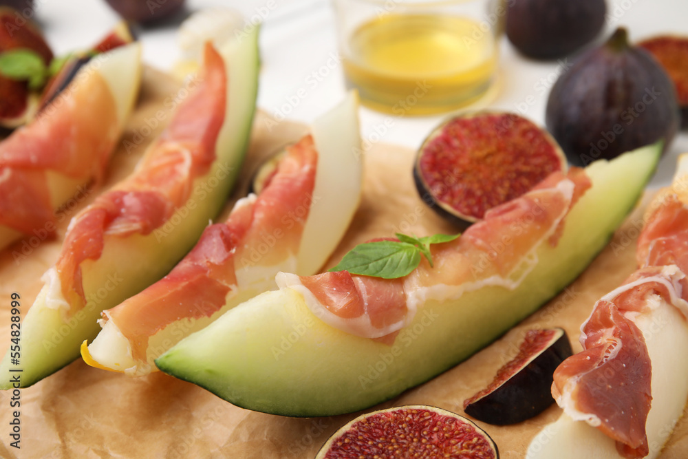 Tasty melon, jamon and figs served on parchment, closeup Tasty melon, jamon and figs served on parchment, closeup