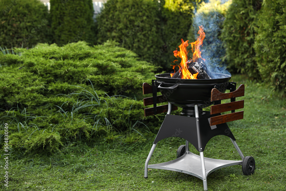 Portable barbecue grill with fire flames outdoors. Space for text Portable barbecue grill with fire flames outdoors. Space for text