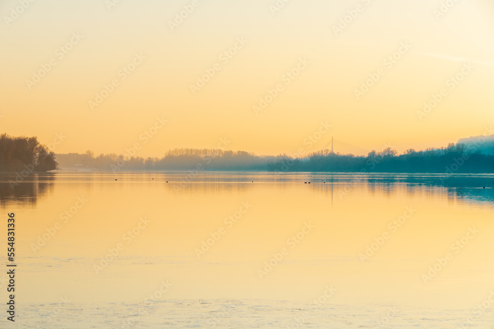 A foggy evening during an amazing colorful sunset with reflections over the Pietersplas pond in Maastricht, creating an magical and mysterious atmosphere in nature. The poles gives a nice reflection A foggy evening during an amazing colorful sunset with reflections over the Pietersplas pond in Maastricht, creating an magical and mysterious atmosphere in nature. The poles gives a nice reflection