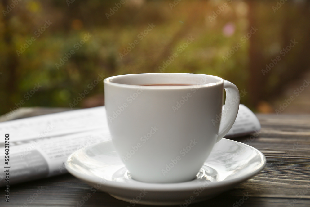 White cup with coffee and newspaper on wooden table, closeup. Morning ritual White cup with coffee and newspaper on wooden table, closeup. Morning ritual