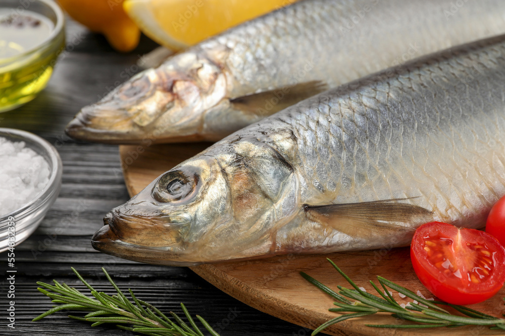 Delicious salted herrings and ingredients on black wooden table, closeup Delicious salted herrings and ingredients on black wooden table, closeup