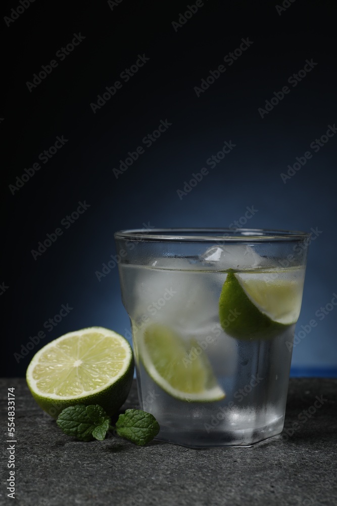 Glass of vodka with lime slices, mint and ice on grey table Glass of vodka with lime slices, mint and ice on grey table